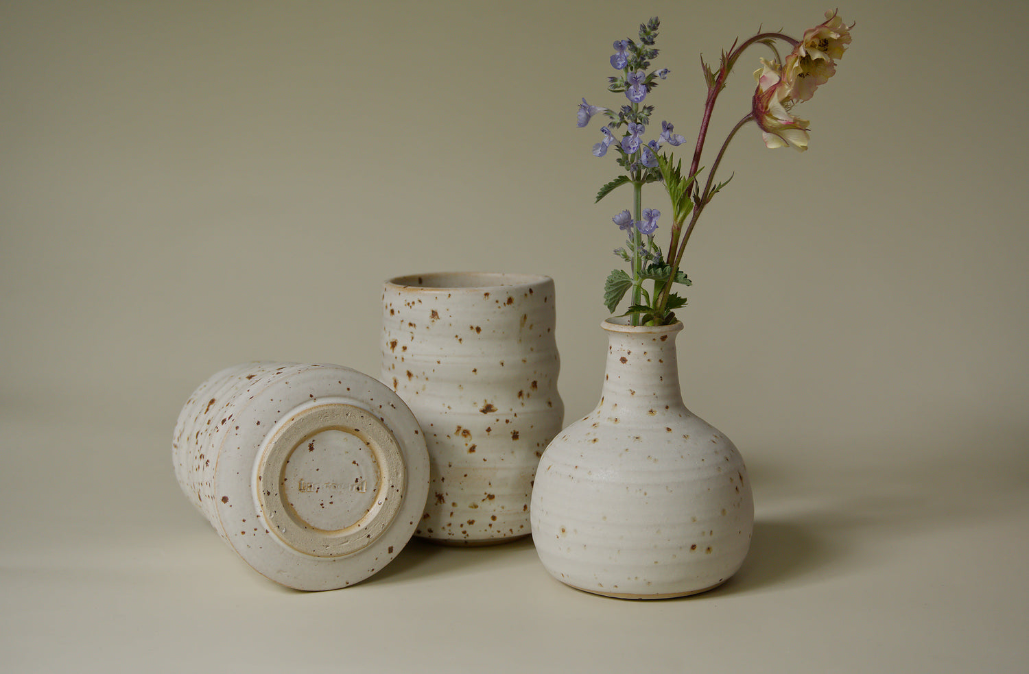 Yunomi cups and chubby bud vase in a white glaze with rust brown iron specks